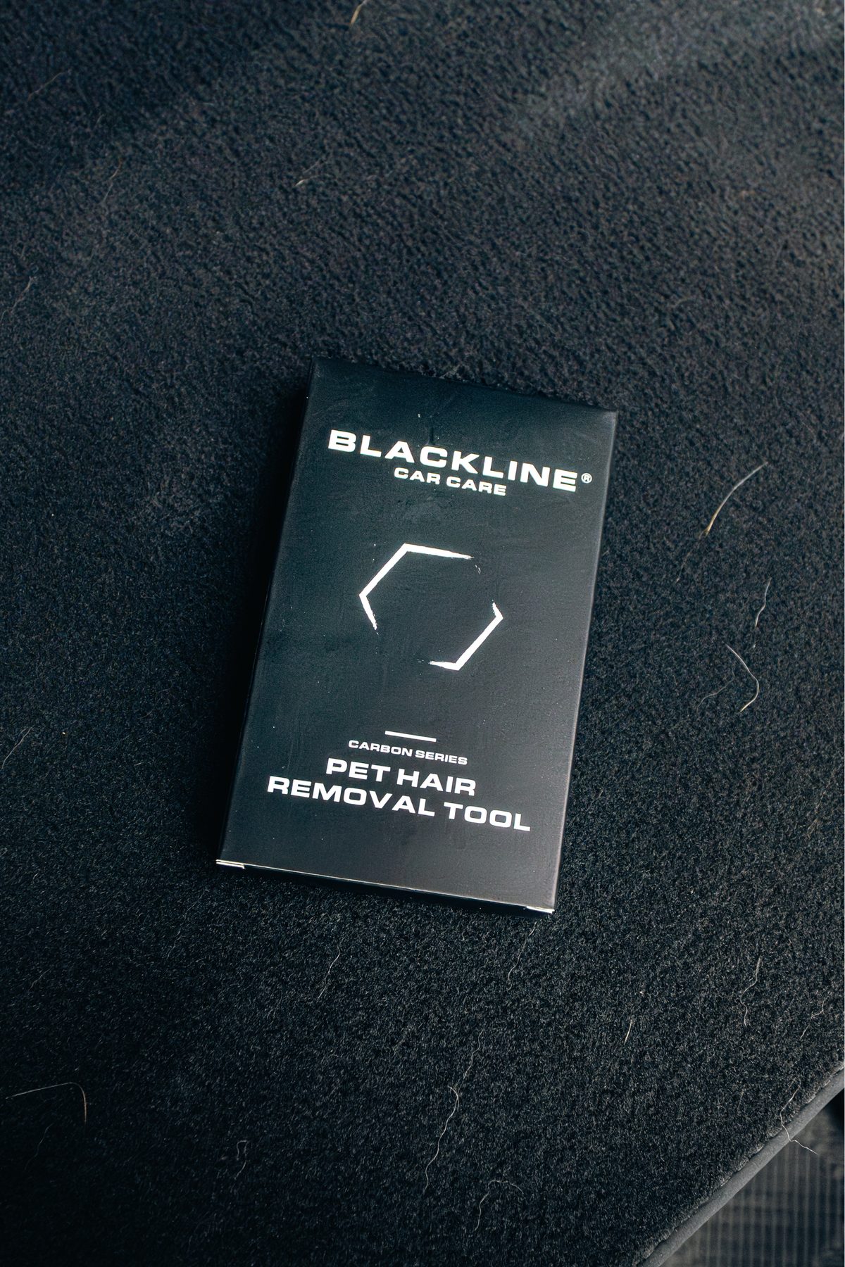 BLACKLINE pet hair brush packaging on a dark fabric surface